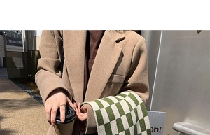 Close-up of green and white checkered knit scarf paired with a camel wool blazer coat