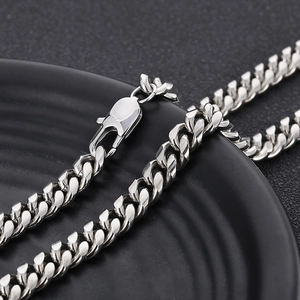 Detail of silver titanium steel Cuban chain necklace with lobster clasp on black plate