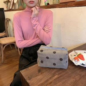 Detail of grey corduroy polka dot pouch with a contrast blue zipper on a cafe table