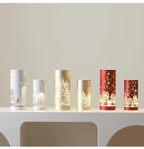 Detailed view of glowing Christmas pillar lights with snowflake and star cutouts