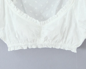 Dettaglio del top in pizzo bianco Broderie Anglaise con scollo a volant ed elastico