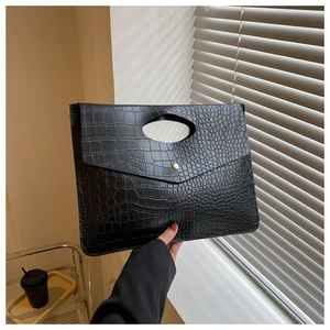 Detail of black crocodile texture envelope clutch bag with elegant golden metallic buckle
