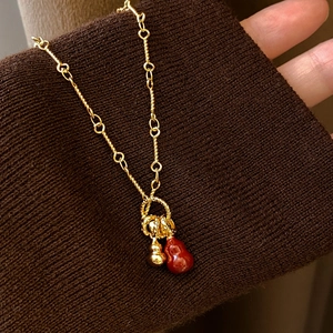 18k gold plated double gourd pendant necklace with red agate on a dark knit fabric