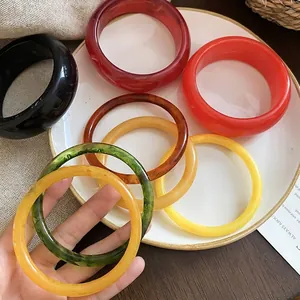Minimalist resin round bangles in vibrant colors on a white plate and wood background