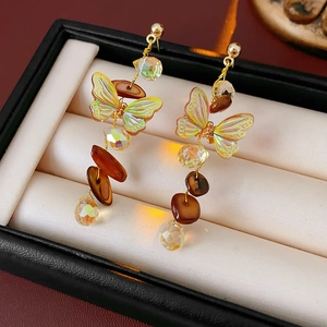 Dettaglio macro di orecchini vintage a farfalla con frange in conchiglia e ganci dorati