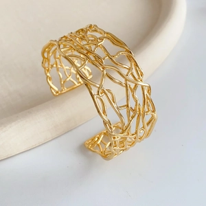 Vue détaillée de la structure entrecroisée ajourée du bracelet jonc large plaqué or brillant