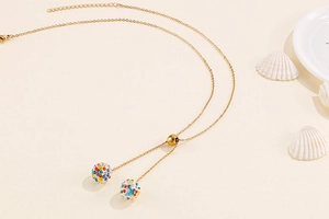 Detail of gold thin chain necklace with multi-color crystal paved ball pendants