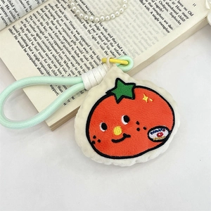 Macro shot of plush tomato keychain with green braided rope on an open book background