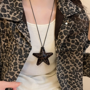 Close-up of leopard print star pendant necklace worn over a denim jacket