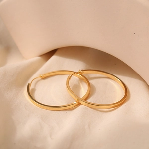 Macro shot of 18K gold plated minimalist hoop earrings on soft cotton fabric