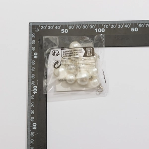 Close-up measurement of large white faux pearls with silver lobster clasp on a scale
