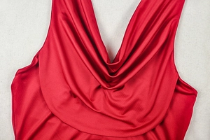Detail eines roten Satinkleids mit tiefem V-Ausschnitt und eleganten Wasserfallfalten