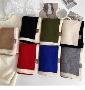 Close-up of various knitted scarves in multiple colors with contrasting white borders