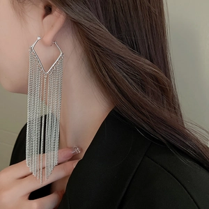Close-up of long silver metallic chain fringe earrings worn with a black blazer