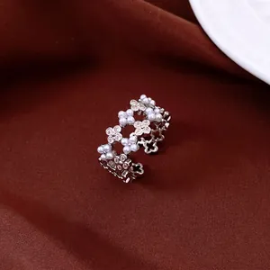 Détail d'une bague fleur argentée ajustable avec perles et zircons sur de la soie rouge