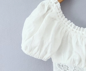 Détail du haut blanc à manches bouffantes avec encolure élastique et texture de broderie
