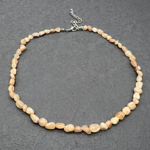 Detailed macro of irregular natural orange quartz stone necklace with silver lobster clasp