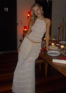 Detail of off-white pleated two-piece set featuring a halter top and tiered maxi skirt