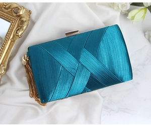 Detail of teal satin evening clutch featuring pleated texture and gold metal clasp