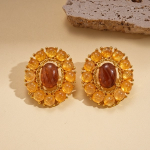 Vista de detalle de pendientes retro de ágata con cristales de ámbar sobre piedra beige