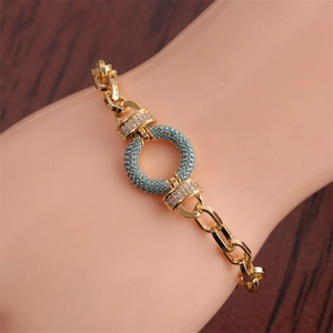 Detail of gold hip hop bracelet with blue turquoise and white cubic zirconia on a wrist