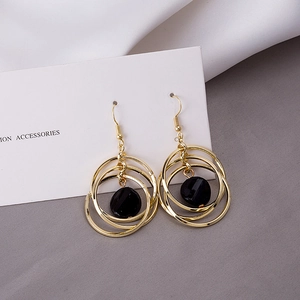 Detailed shot of layered gold triple hoop earrings featuring a central black bead pendant