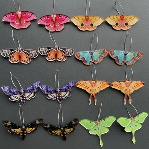 Flat lay of 12 pairs colorful acrylic butterfly and moth earrings with silver hoops