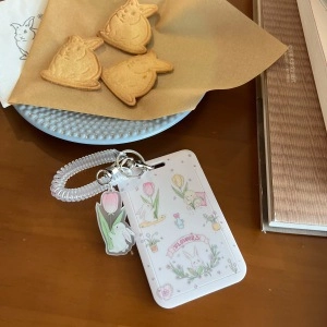 Detailed view of white bunny card holder with floral print and elastic wrist strap
