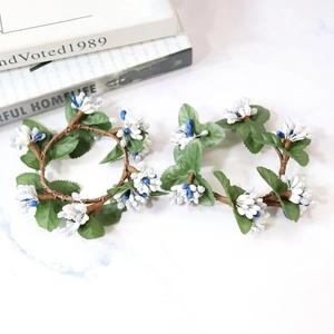 Artificial white berry wreath with green leaves and blue accents on marble surface