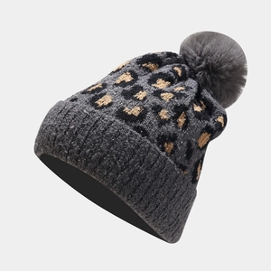 Close-up of leopard print knit beanie with fuzzy pompom and thick folded cuff details