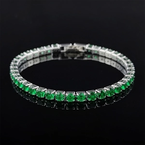 Macro detail of silver tennis bracelet featuring round cut green emerald-style zircons