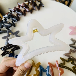 Detail view of colorful star-shaped hair claws with golden metal springs and matte finish