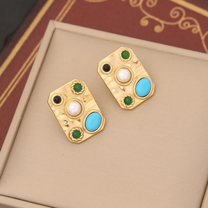 Macro shot of gold hammered earrings featuring pearls, turquoise, and colorful gemstones