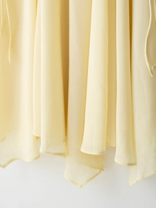 Detailed view of light yellow chiffon fabric with natural ruffles and soft draping texture