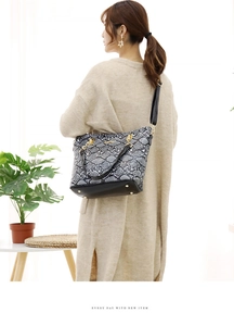 Asian model wearing a gray snakeskin print tote bag with gold hardware in a bright room