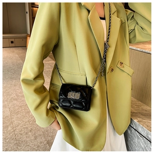 Quilted black chain bag with silver buckle shown on a light green blazer outfit