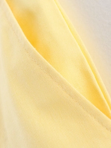 Detailed macro shot of pale yellow cotton twill fabric showing fine stitching and texture