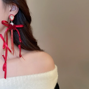 Détail de boucles d'oreilles nœud rouge avec pompons en cristal et perle pendante