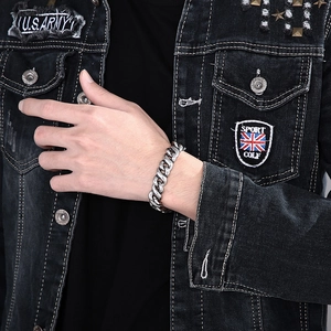 Close-up of vintage stainless steel curb chain bracelet worn with a punk denim jacket
