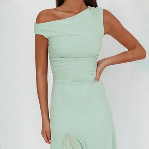 Detail of light green one-shoulder dress with elegant pleats and side leg slit