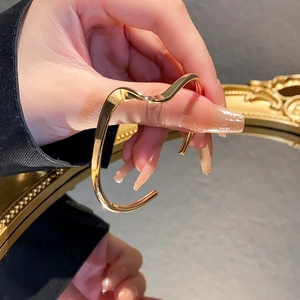 Detailed view of a golden wavy irregular bracelet featuring a polished metallic finish