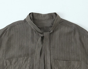 Detail of taupe striped shirt showing bow-tie collar and front flap pockets