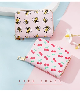 Detail view of pink card holders with cute bee and cherry patterns and golden zippers