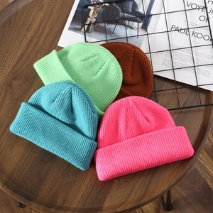 Solid color ribbed knit beanies in mint, blue, caramel, and magenta on wooden table