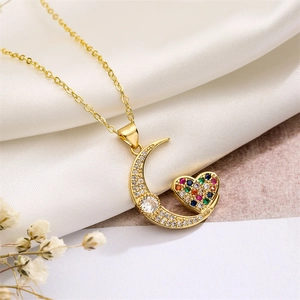 Detail of gold crescent moon and heart necklace with colorful zircon on white silk