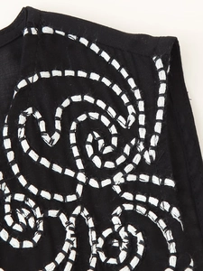 Close-up of white spiral embroidery details on a black fabric V-neck ethnic style blouse