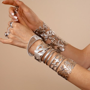 Detail of silver ginkgo leaf and flower bangles with geometric open metal bracelets