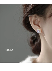 Detailed view of 14mm mermaid pearl stud earrings with iridescent glow on ear