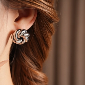 Detail of silver twisted knot stud earring on model showing minimalist metal design