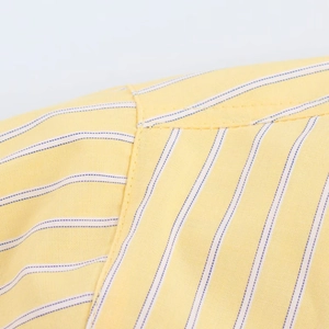Macro-opname van schoudernaad op een geel gestreept poplin overhemd voor dames